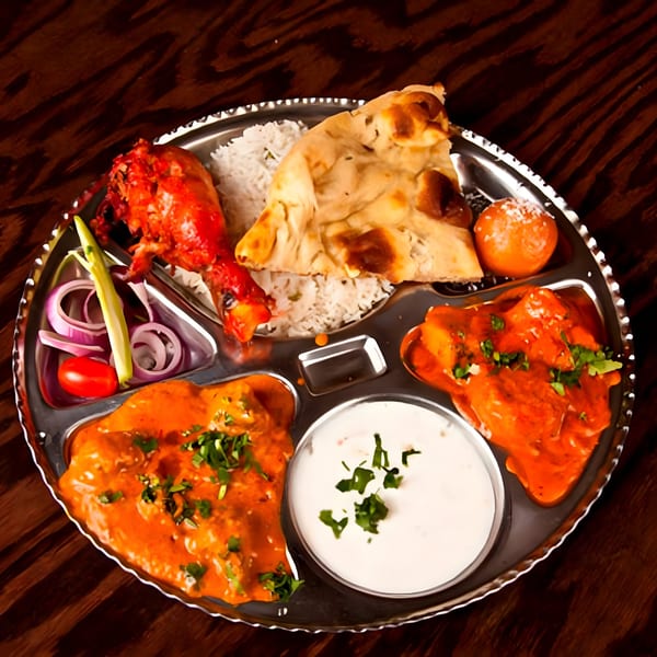 A Swagat Fine Indian Cuisine thali with chicken tikka, butter chicken, rice, naan, raita, and gulab jamun.